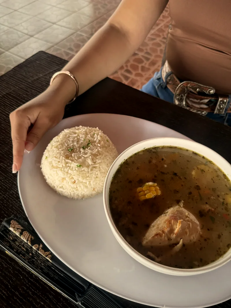 Vista superior de una sopa con maíz y pollo, servida junto a arroz blanco