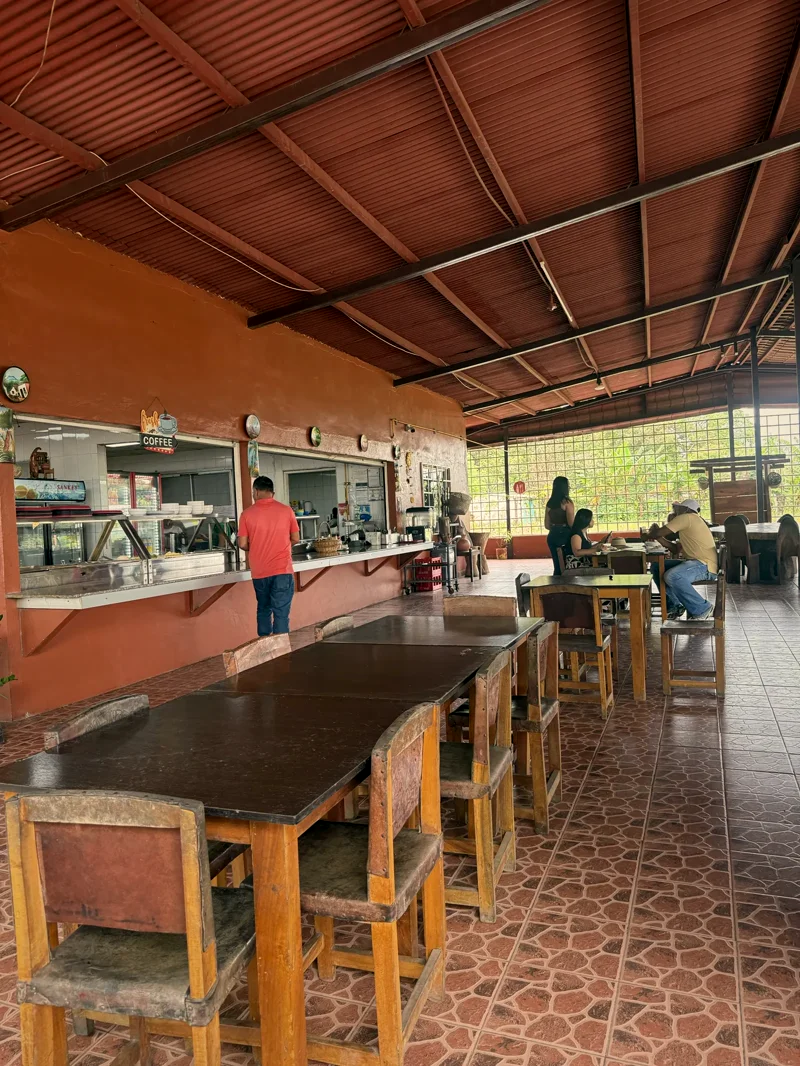 Barra de despacho de la cocina con letrero Fresh Coffee y mesas del comedor