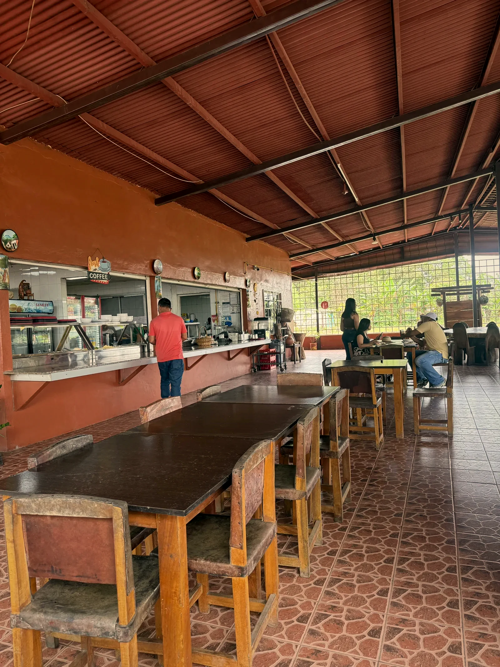 Barra de despacho de la cocina con mesas del comedor al fondo