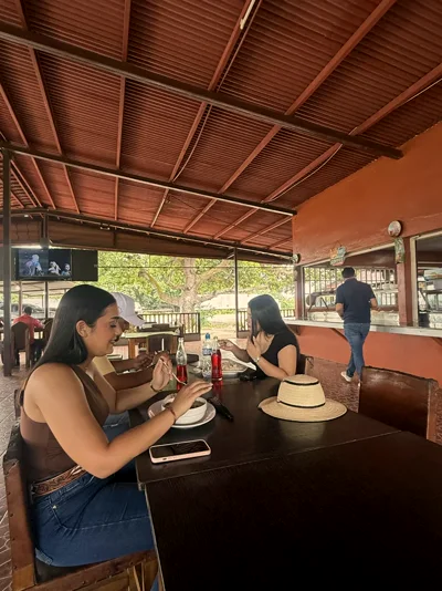 Amigas comiendo en el rancho con una gaseosa, sombrero sobre la mesa
