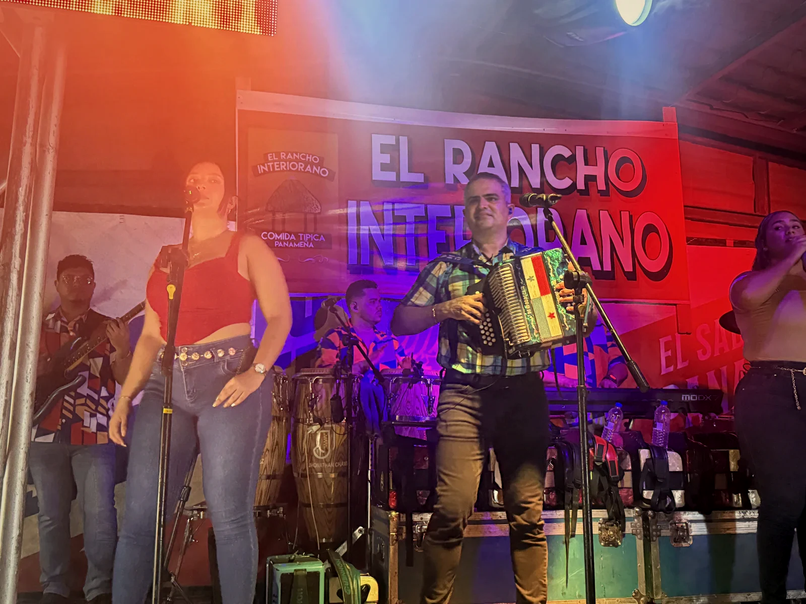 La orquesta de Jhonathan Chávez tocando en la tarima de El Rancho Interiorano, con el banner del negocio detrás